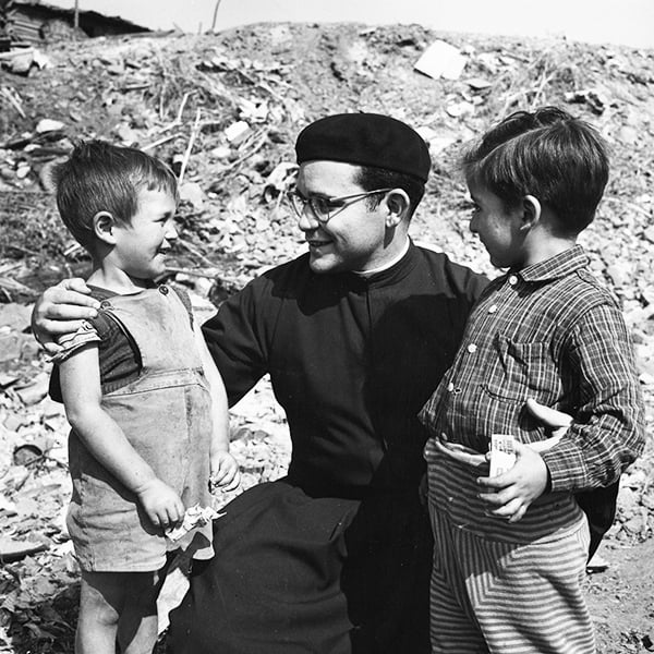 Father Maryknoll Miguel d'Escoto smiles with two children during his missionary service in Chile.