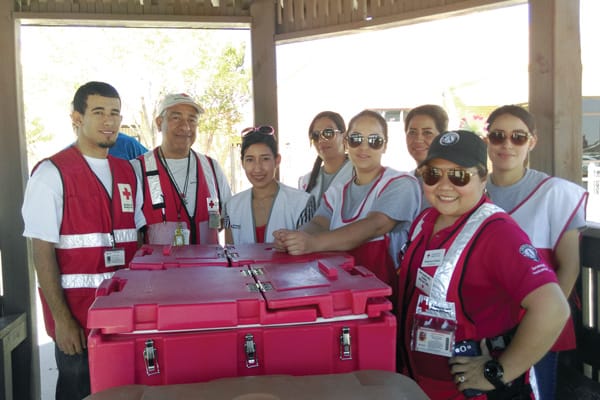 A group of Red Cross volunteers pause for a photo, including undocumented immigrants Jefferson Taborda, left, and his father, Jorge, next to him in a white cap.