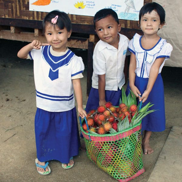 Mercy messenger: Tots at day care center in camp in north Myanmar haul fruit delivered by Maryknoll.