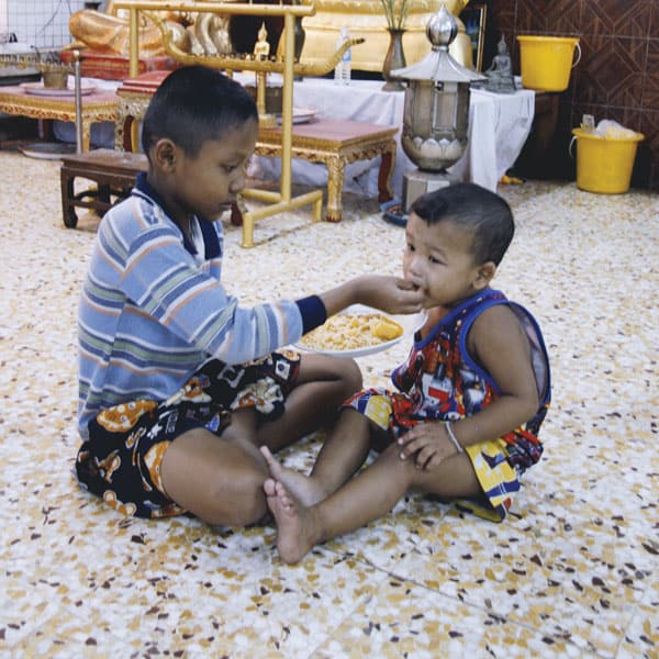 Mercy messenger: A student in school in Thailand for displaced Burmese feeds a deaf child who lives there.