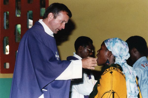 Father Michael Snyder, a Maryknoll missionary priest, gives Communion to an African woman in Tanzania.