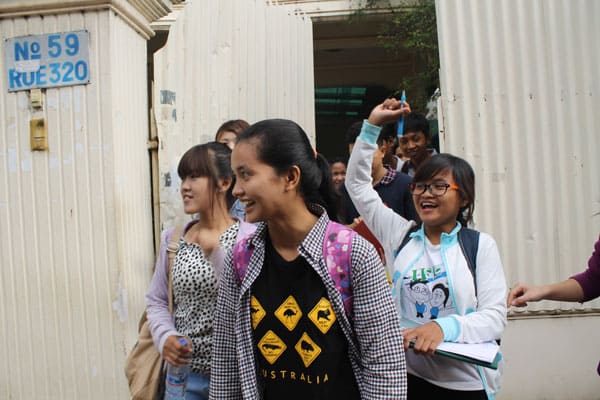 Raksmy, a young Cambodian woman living in in Phnom Penh, raises her arm as if in a cheer with a group of other university student.