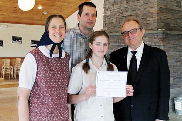 As Susan and Jeremy Maendel proudly look on, their daughter Riva Maendel, an eighth-grader at the Bruderhof community's Fox Hill School in Walden, N.Y., accepts her first-place $1,000 award from Maryknoll Brother John Blazo (right). (A. Marsolek/U.S.)