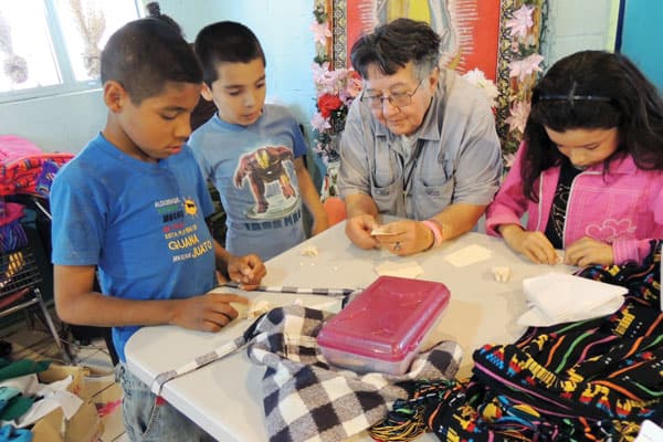 Empowering women in Ciudad Juarez. In the photo, Sister Sierra teaches children who attend the homework program to make frogs and other paper figurines.