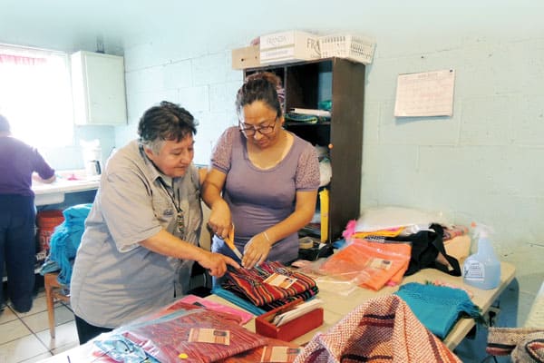 At Santa Catalina center in Ciudad Juarez, Mexico, Maryknoll Sister Margaret Sierra (left) encourages Iris Ivarra and the other women in the sewing cooperative who make and sell products to support themselves and their families.