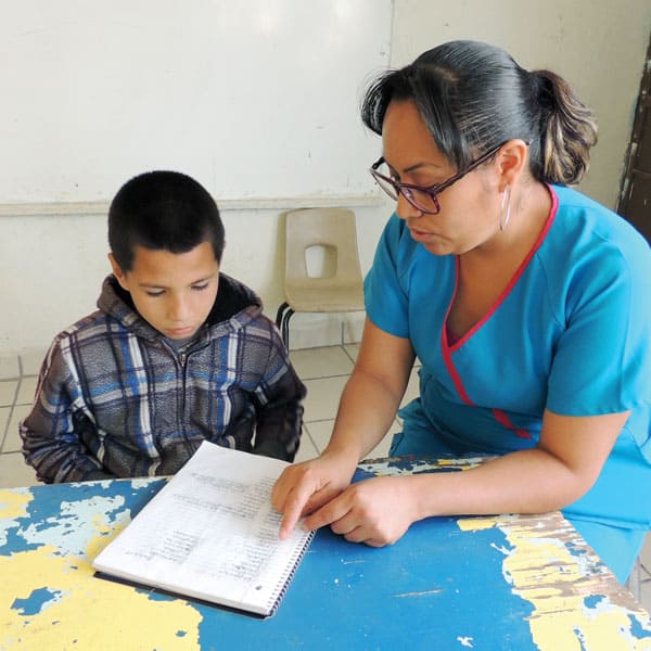 Julia Gutierrez, a tutor at Santa Catalina center in Ciudad Juarez, Mexico, helps a child from the colonia Panfilo Natera with his homework.