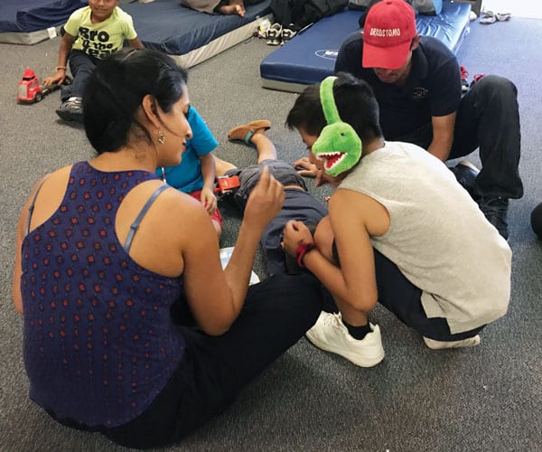 Helena Niño de Guzman, a Wisconsin kindergarten teacher on mission immersion trip, plays with young separated migrants at Loretto-Nazareth Migrant Center in El Paso, Texas. (D. Kelly/U.S.)