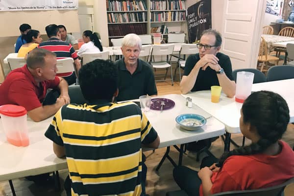 On immersion trip (l. to r.) Chuck Peabody, Scott Wright and Gerry Lee talk with separated migrants reunited at Annunciation House in El Paso. (D. Kelly/U.S.)