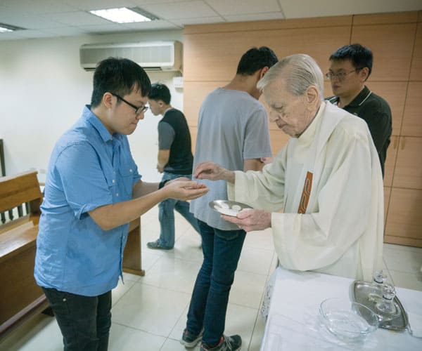 Father Doyle Helps Foster Catholic Friendship and Love in Taiwan: Father Doyle distributes Holy Communion at evening Mass at Friendship House. (Nile Sprague/Taiwan)