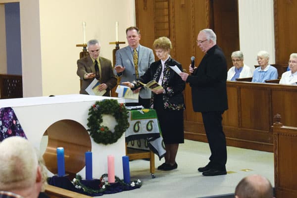 13 Missioners sent forth: Maryknoll leaders (l. to r.) Richard Lessard (Affiliates), Ted Miles (Lay Missioners), Sister Antoinette Gutzler (Sisters), Father Raymond Finch (Fathers and Brothers) bless mission crosses for new missioners at sending ceremony. (B. Bachmann/U.S.)