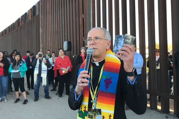 Bishop Mark J. Seitz of El Paso, Texas, holds photos of two migrant children who died in U.S. custody; he spoke during the Feb. 26 Interfaith Service for Justice and Mercy at the border near Sunland Park, N.M. (CNS photo/David Agren)