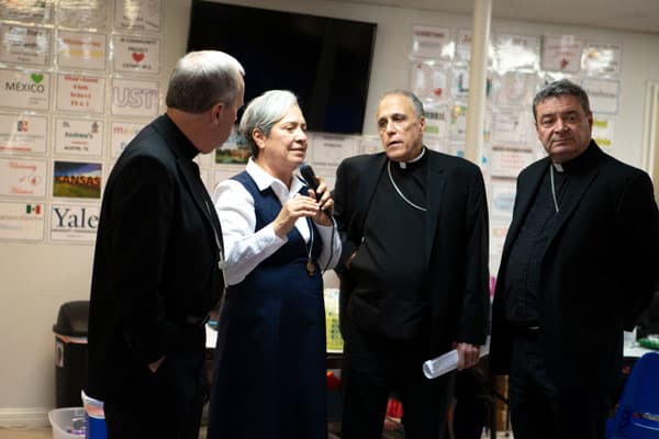 Sister Norma Pimentel, a member of the Missionaries of Jesus, who is executive director of Catholic Charities of the Rio Grande Valley in Texas and a longtime advocate for immigrants and refugees, speaks to an audience July 1, 2018, as she shows a delegation of U.S. bishops a respite center for new immigrant arrivals in McAllen, Texas. Pictured from left, are Bishop Joseph C. Bambera of Scranton, Pa., Cardinal Daniel N. DiNardo of Galveston-Houston and Auxiliary Bishop Robert J. Brennan of Rockville Centre, N.Y. (CNS photo/Chaz Muth)