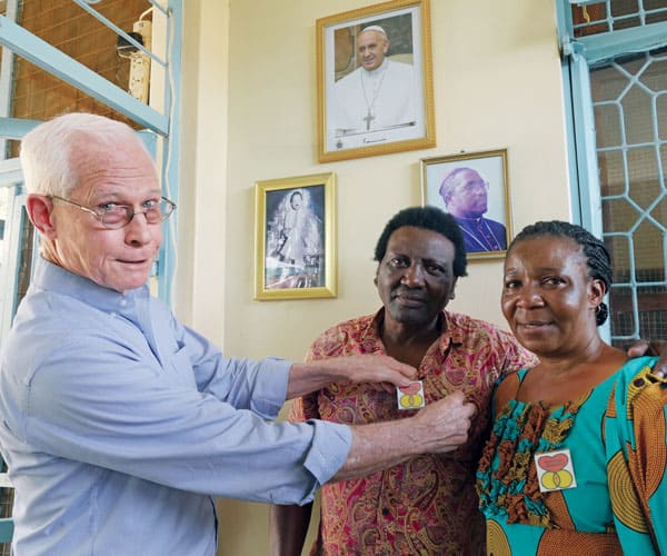 Maryknoll Father John Eybel, who as assistant pastor at Transfiguration parish in Mabatini assist with the church's holistic ministry, awards Marriage Encounter pins to Anton and Eugenia Msafiri. The couple had completed a Marriage Encounter weekend to help them strengthen their relationship.