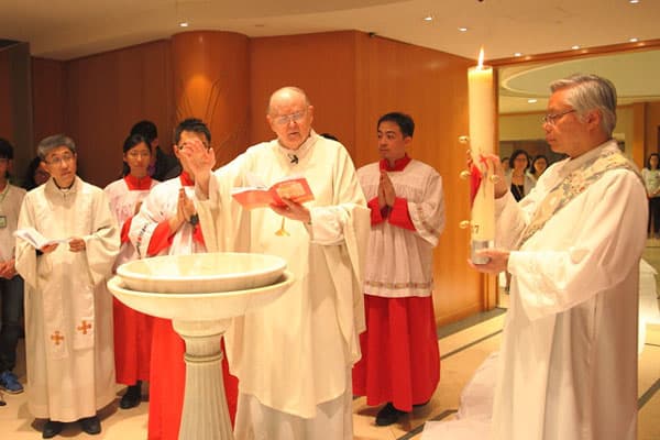 Evangelizing among skyscrapers - Father Cuff blessing the water before celebrating a baptism at Our Lady of Mount Carmel parish in Hong Kong.