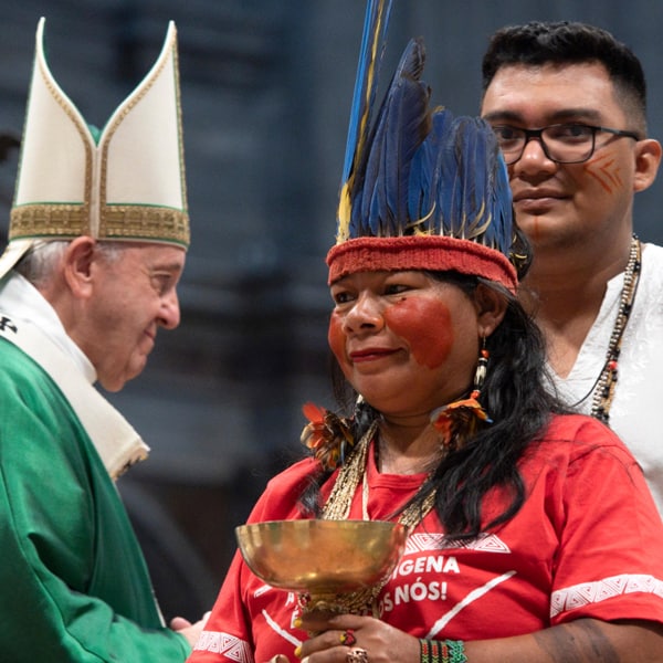 An indigenous woman in a feathered headdress presents an offertory gift as Pope Francis celebrates the opening Mass of the Synod of Bishops for the Amazon in St. Peter's Basilica at the Vatican Oct. 6, 2019. Some bishops say indigenous culture can enrich Catholic liturgy. (CNS/Vatican Media)