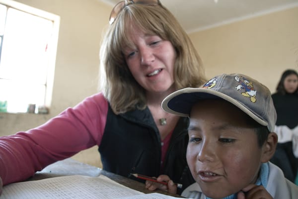 As a Maryknoll lay missioner in Amachuma, Maggie Fogarty helps a young neighbor with his schoolwork as he and modern shepherds in Bolivia reflect the face of God to her. (S. Sprague/Bolivia)