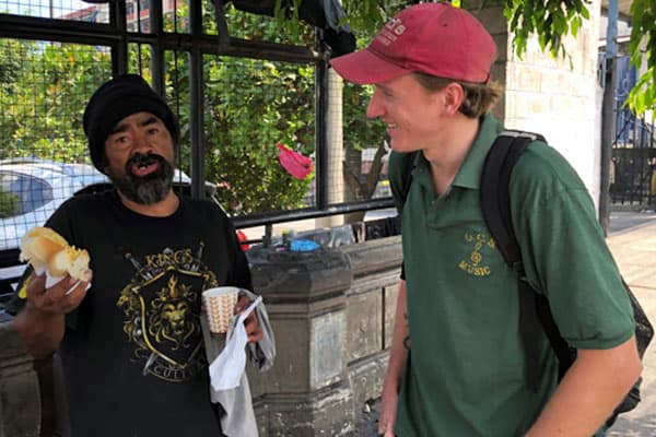 Tim Ross, right, talks with Louis, who is homeless in El Salvador, as the Maryknoll lay missioner completes a bread-and-coffee route near the general hospital in San Salvador. (Meinrad Scherer-Emunds/El Salvador)