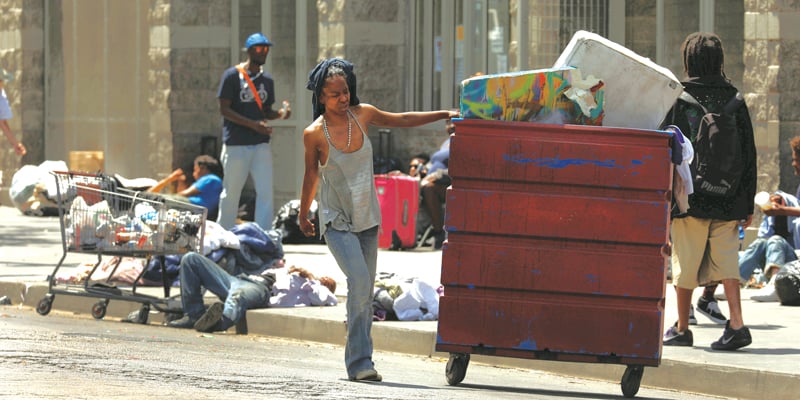 LA Homelessness: A woman (at left) pushes a cart with her belongings in downtown Los Angeles.