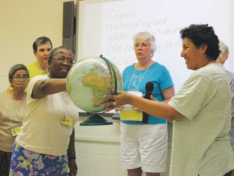 Maryknoll Sisters Claris Zwareva (l.) and Rosalva Sandi hold a globe during a discussion on bioregional theology at the Maryknoll Mission Institute. (Courtesy of Maryknoll Sisters/U.S.)