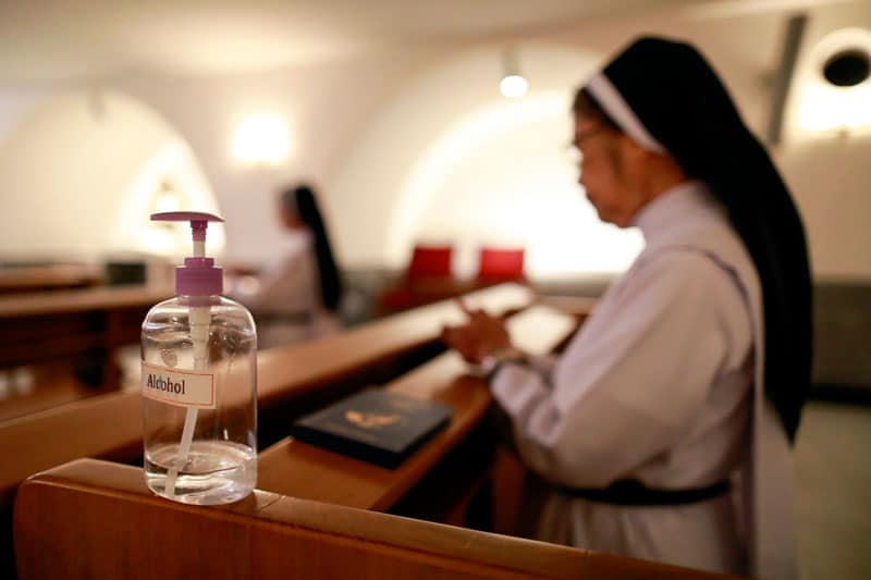 Covid-19 in Southeast Asia: A nun prays next to a container of hand sanitizer as a priest celebrates Mass in a chapel of the cathedral in Manila, Philippines, March 15, 2020. The Mass was livestreamed on Facebook following the suspension of large gatherings due to the coronavirus pandemic. (CNS photo/Eloisa Lopez, Reuters)