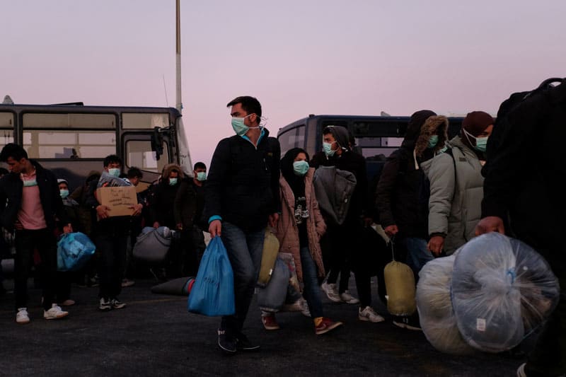 Migrants wearing protective face masks as a precaution against COVID-19 prepare to board a ferry to mainland Greece; they were at the port of Mytilene, on the island of Lesbos, March 20, 2020. (CNS photo/Elias Marcou, Reuters)