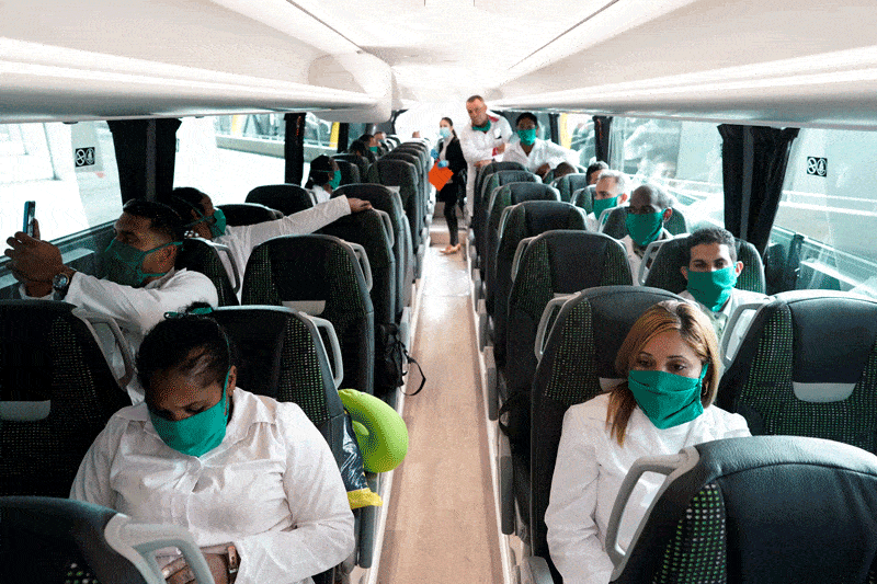 viral genocide warning: Cuban doctors are seen inside a bus at Madrid's Adolfo Suarez Barajas Airport March 29, 2020. The doctors will work in Andorra during the COVID-19 pandemic. In a March 28 letter, Pope Francis said he was "edified by the reaction of so many people -- doctors, nurses, volunteers, religious men and women and priests -- who risk their lives to heal and defend healthy people from contagion." (CNS photo/Juan Medina, Reuters)
