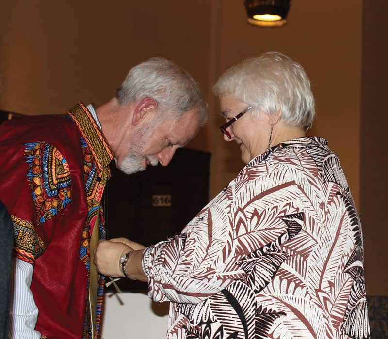 Marj Humphrey, director of missions for the Maryknoll Lay Missioners, presents a mission cross to Greg Garrity at the group’s sending ceremony for new missioners in December 2019. (Deborah Northern/U.S.)