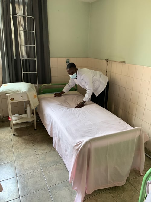 Charles Ogony, a Maryknoll seminarian from Kenya, makes a bed at a senior home run by the Little Sisters of the Abandoned Elderly in Cochabamba, Bolivia. (Matthew Sims/Bolivia)