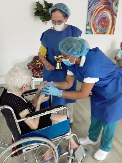 Sister Geraldine Brake and one of the aides at Fundación Nueva Vida in Panama give the consecrated host to one of the elderly residence during a prayer service during Holy Week. (Courtesy of Geraldine Brake/Panama)