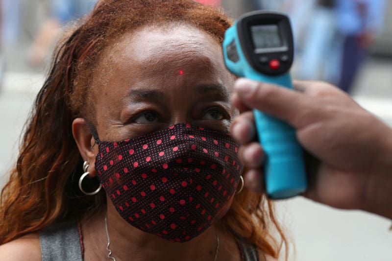 An employee checks the temperature of a woman before she enters a shop in Sao Paulo June 10, 2020, during the COVID-19 pandemic. (CNS photo/Amanda Perobelli, Reuters)