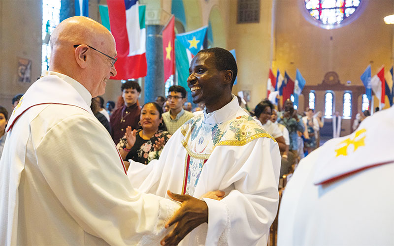 Father Ogony greets Maryknoll Father William LaRousse during the Sign of Peace. (Octavio Durán/U.S.)